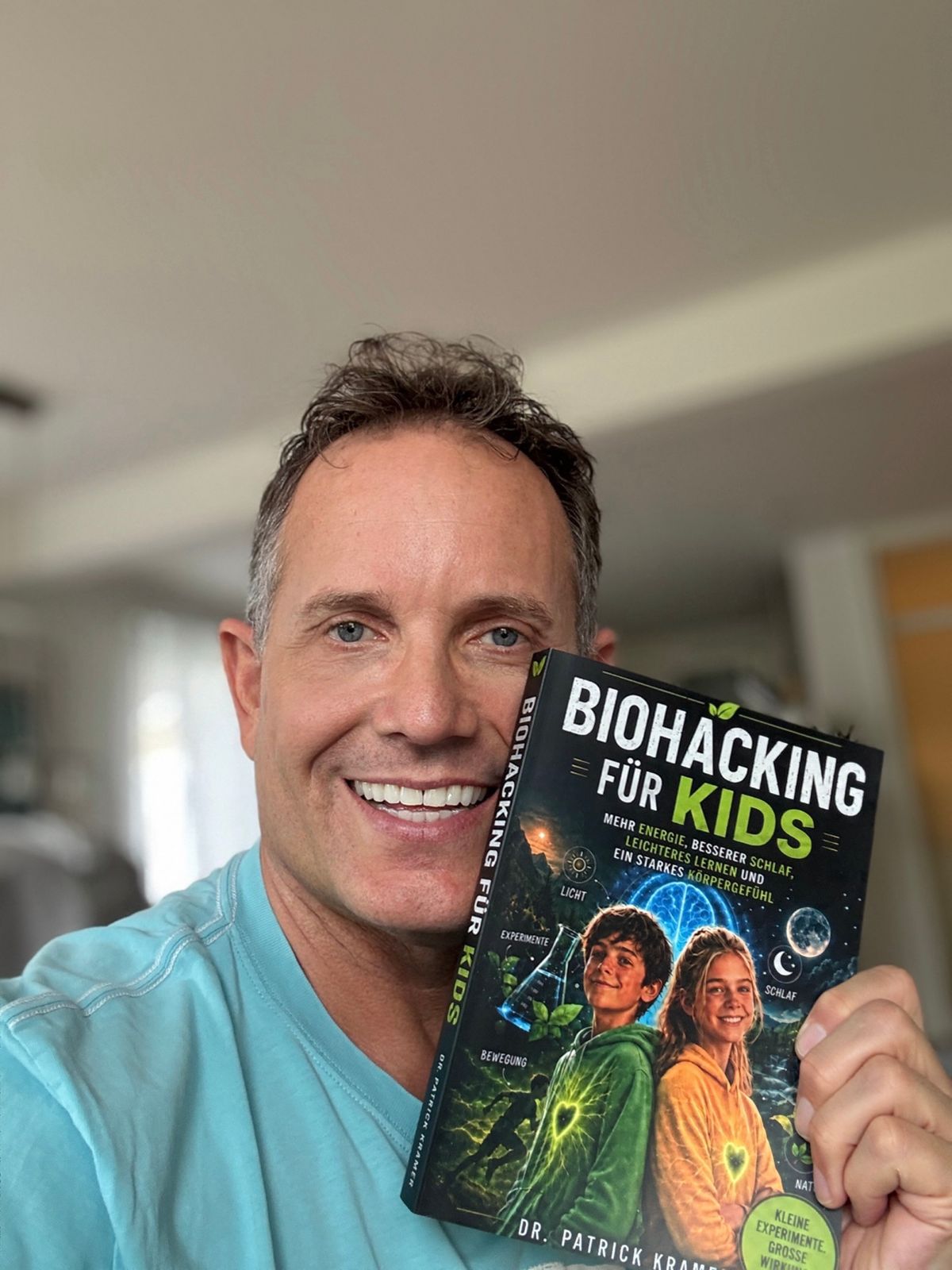 Dr. Patrick Kramer hält sein Buch „Biohacking für Kids“ in die Kamera